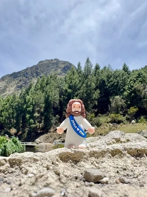 A small figure of Jesus on the rocks below a mountain